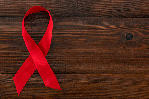 Красная лента - символ осознания СПИДа на деревянном фоне с
 - Фото, изображение
