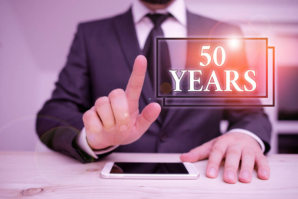 Writing note showing 50 Years. Business photo showcasing Honoring Ruby Jubilee Commemorating a special day Semicentennial Male human wear formal clothes present use hitech smartphone. - Photo, Image