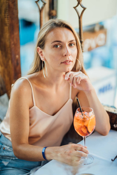 Beautiful young woman in cafe with cold cocktail in hot summer day - Photo, Image
