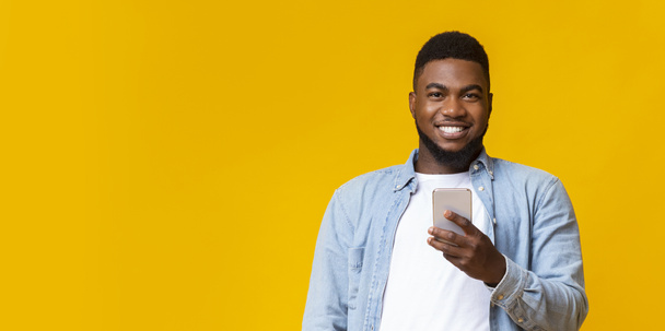 Ritratto di ragazzo nero sorridente con smartphone in mano
 - Foto, immagini