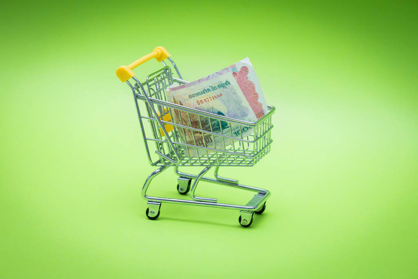 Carrinho de compras em miniatura com dinheiro cambojano, Won. O conceito de compras e o poder da economia
.  - Foto, Imagem