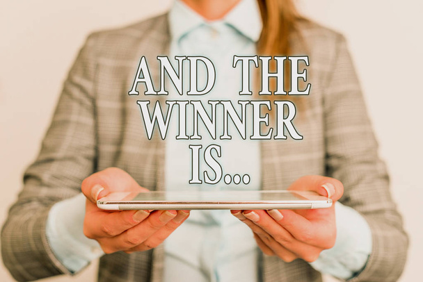 Handwriting text writing And The Winner Is. Concept meaning Announcing who the Victor is Exemplar Achiever Business concept with mobile phone and business woman. - Photo, Image