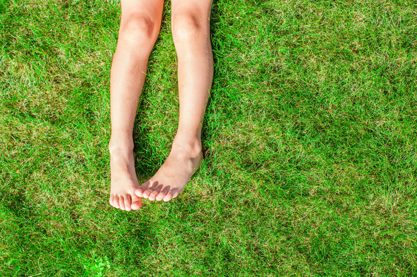 Close-up of two legs of a young girl on the grass on the lawn - Photo, Image