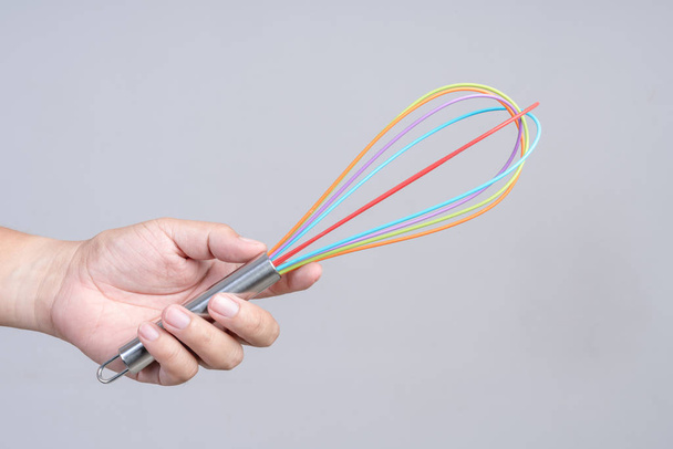 Hand holding colorful wire whisk or egg beater - Photo, Image