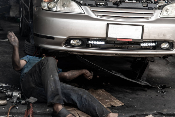Un mecánico está reparando la suspensión delantera del coche en el repai
 - Foto, Imagen