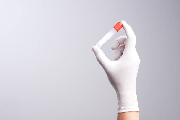 Hand with latex glove holding empty test tube - Fotoğraf, Görsel
