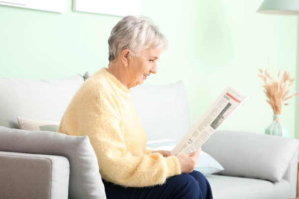 Senior žena s naslouchátkem čtení novin doma - Fotografie, Obrázek