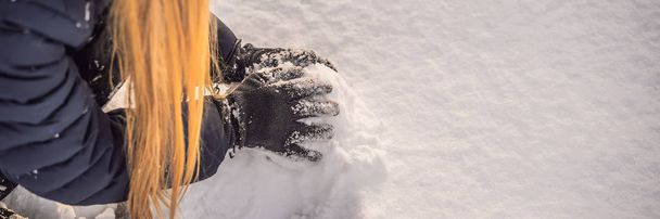 Young woman rolling giant snowball to make snowman BANNER, LONG FORMAT - 写真・画像