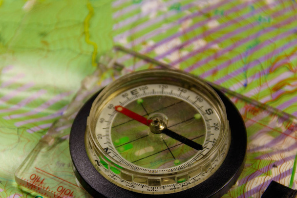 Magnetický kompas se nachází na topografické mapě. Orientační běh v divočině. Cestování a dobrodružství koncept - Fotografie, Obrázek