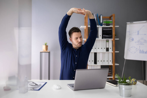 Giovane imprenditore stretching sul posto di lavoro in ufficio
 - Foto, immagini