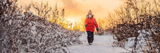 Cute boy in red winter clothes runs fun in the snow. Winter Fun Outdoor Concepts BANNER, LONG FORMAT - 写真・画像