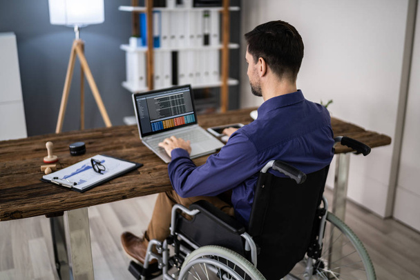 Businessman On Wheelchair While Working On Computer - Foto, Bild