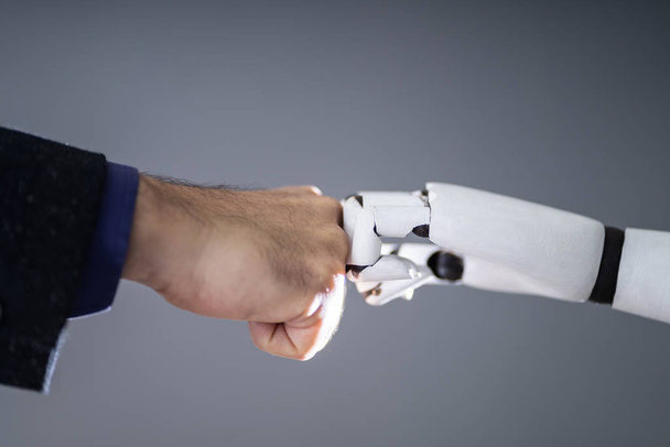 Robotti ja ihmisen käsi Making nyrkki kolahtaa harmaa tausta
 - Valokuva, kuva