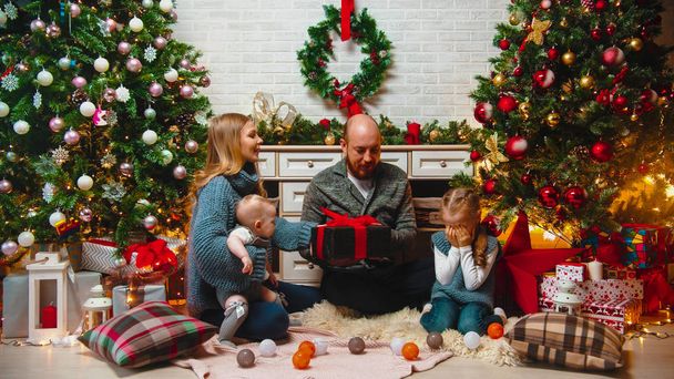 Conceito de Natal - família feliz senta-se no cenário de Natal e presentes de troca - uma menina sentada com os olhos fechados
 - Foto, Imagem