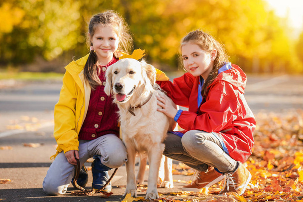 Χαριτωμένα κορίτσια με σκύλο στο πάρκο φθινόπωρο - Φωτογραφία, εικόνα