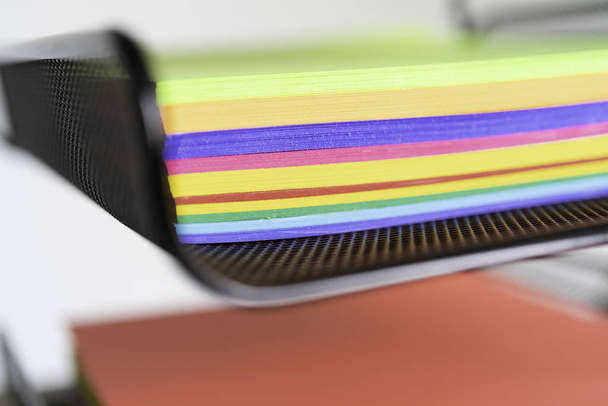 pilha de documentos sobre papel brilhantemente colorido na bandeja empilhada na mesa de escritório
 - Foto, Imagem
