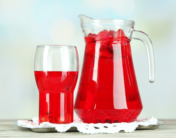Pitcher and glass of compote on napkin on wooden table on light background - Foto, immagini