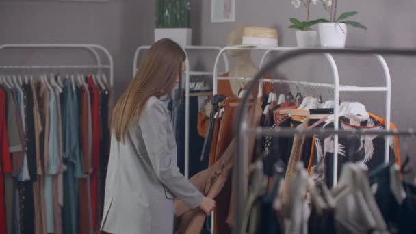 shopping, fashion, style and people concept - happy woman choosing clothes and looking to mirror in mall or clothing store. - Filmagem, Vídeo
