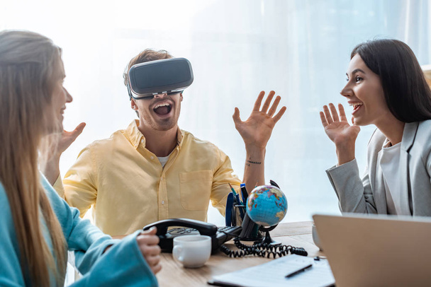 excited young man using vr headset near smiling girlfriend and travel agent - Foto, Imagem