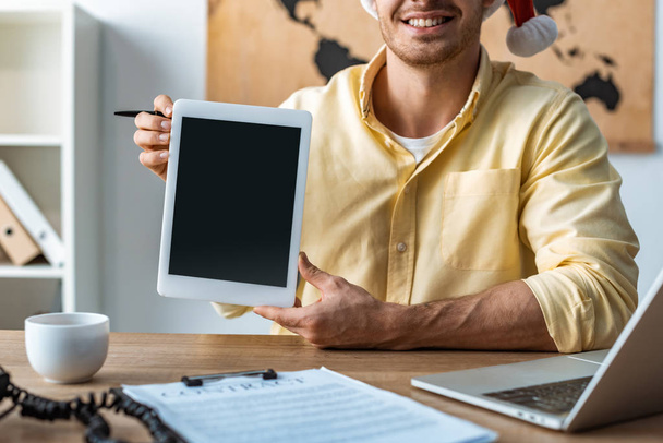 oříznutý pohled usměvavé cestovní kanceláře držící digitální tablet s prázdnou obrazovkou - Fotografie, Obrázek