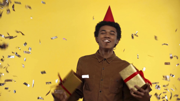 Αφροαμερικάνος έφηβος που κρατάει δώρα απομονωμένα στο κίτρινο - Πλάνα, βίντεο