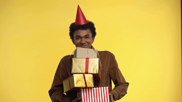 adolescente afroamericano sosteniendo regalos aislados en amarillo
 - Imágenes, Vídeo