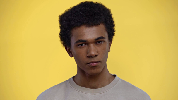 african american teenager looking at camera isolated on yellow - Felvétel, videó