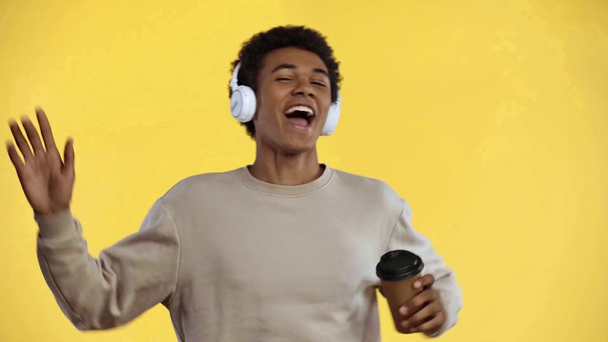 africký americký teenager pití kávy izolované na žluté - Záběry, video