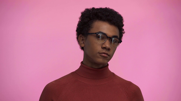 Afrikkalainen amerikkalainen teini katselee kameraa eristetty vaaleanpunainen
 - Materiaali, video