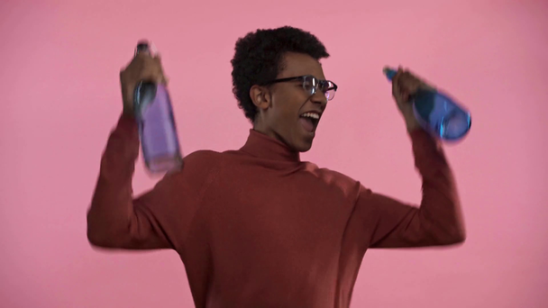 african american teenager dancing with bottles isolated on pink  - Footage, Video