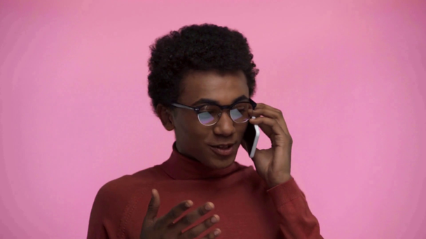 Afrykański amerykański nastolatek mówi na smartfonie odizolowany na różowy - Materiał filmowy, wideo
