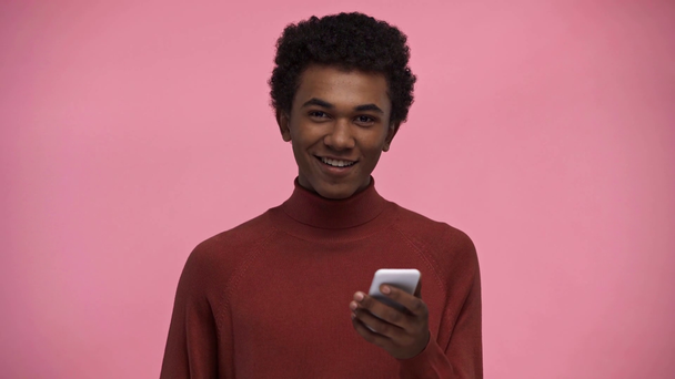 adolescente afro-americano usando smartphone isolado em rosa
 - Filmagem, Vídeo