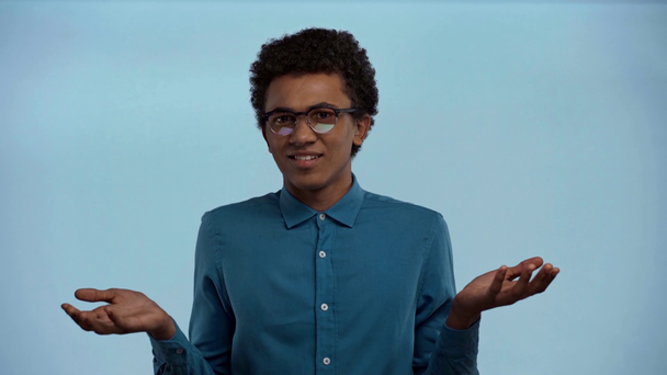adolescente afroamericano con las manos extendidas aisladas en azul
 - Imágenes, Vídeo