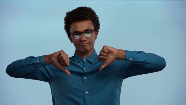 Африканский американский подросток показывает пальцы вниз изолированы на синий
 - Кадры, видео