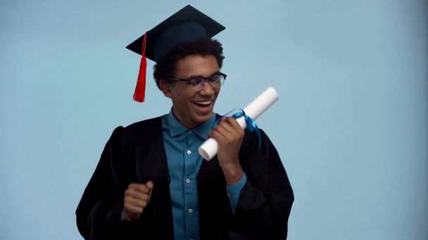 african american teenager dancing with diploma isolated on blue - Séquence, vidéo