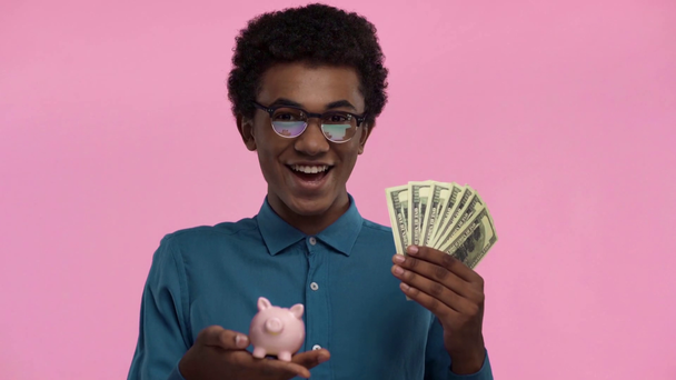 africano americano adolescente holding piggy banco aislado en rosa
 - Imágenes, Vídeo