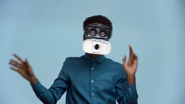 adolescente afroamericano con auriculares de realidad virtual aislados en azul
 - Imágenes, Vídeo