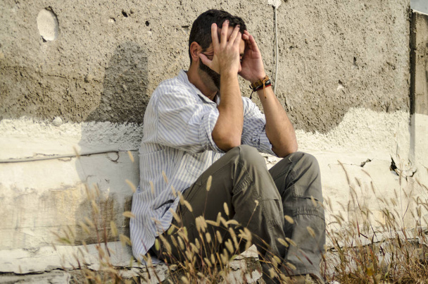 грустный человек, сидящий на земле - Фото, изображение