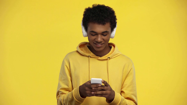 Афріканський підліток, який користується смартфоном, ізольований на жовтому - Кадри, відео