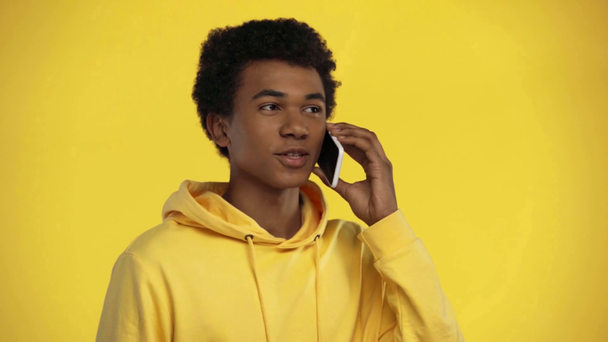 africano americano adolescente falando no smartphone isolado no amarelo
 - Filmagem, Vídeo