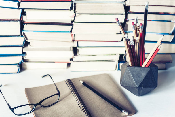 Notebook, pencils, glasses and stack of books, school background - Photo, image