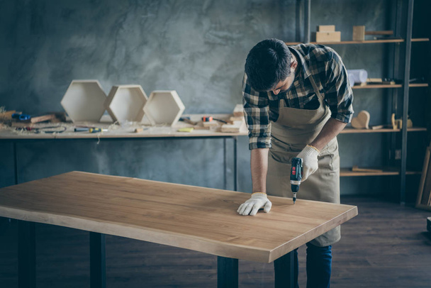Photo of handsome careful guy assembling handmade slab table making finish actions before selling website own wooden business industry woodwork shop garage indoors - Foto, Imagen