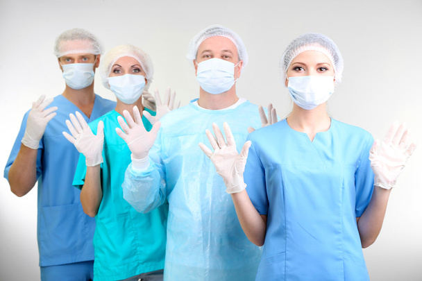 Surgeons standing on grey background - Foto, imagen