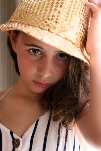 zbliżenie dziewczyna z brązowymi włosami pozowanie w złoty kapelusz - Zdjęcie, obraz