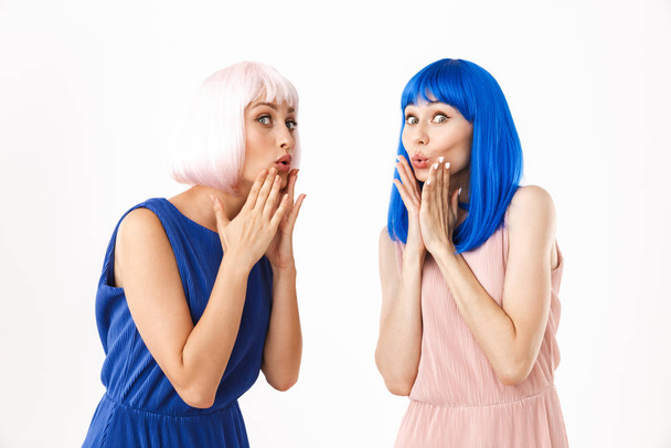 Portrait of two caucasian women wearing blue and pink wigs grimacing at camera - Foto, afbeelding