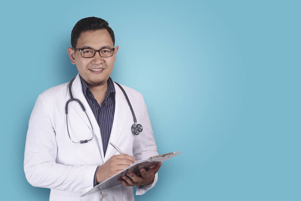 Asian Male Doctor Writing on Clipboard - Photo, Image