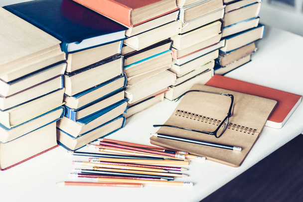 Notebook, pencils, glasses and stack of books, school background - Photo, image