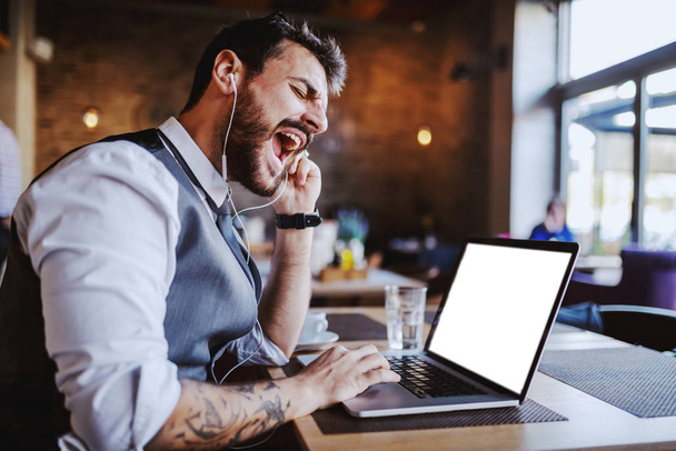 Dühös jóképű kaukázusi elegáns üzletember öltönyben videóhívás laptop, miközben ül a kávézóban. - Fotó, kép