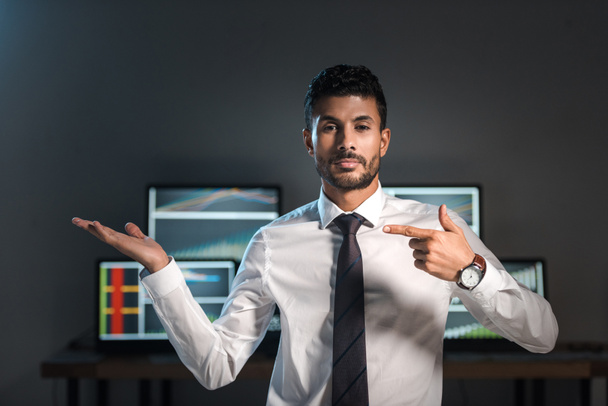 bi-racial trader pointing with finger and computers with graphs on background  - Fotó, kép