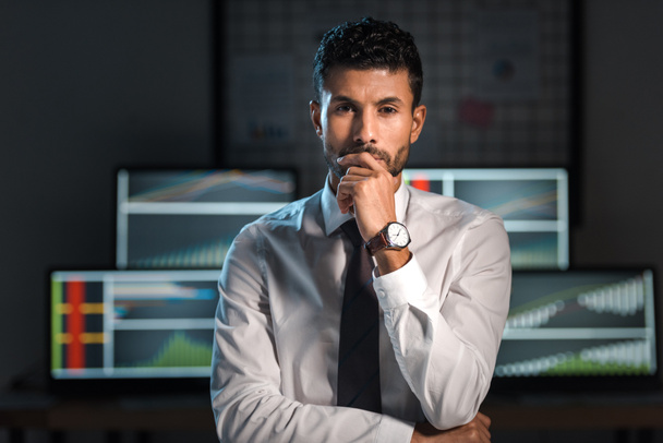 pensive and handsome bi-racial trader looking at camera in office  - Photo, Image